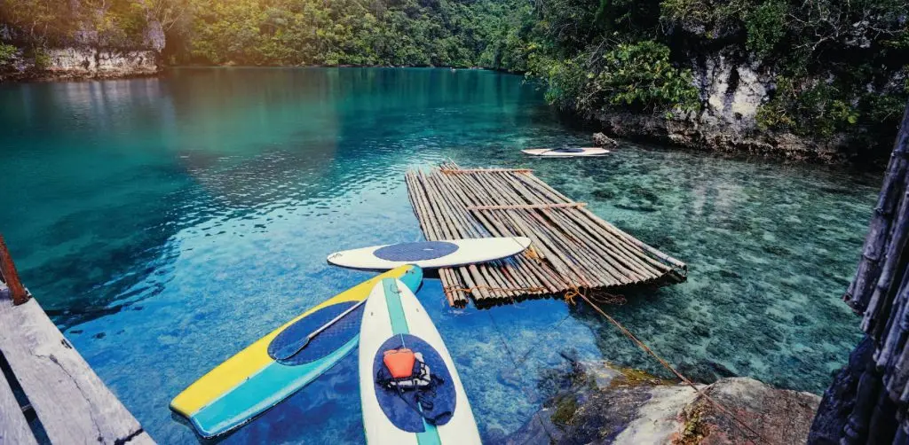 Visitors paddleboarding, kayaking, and jumping from the diving board at Sugba Lagoon, Del Carmen, Siargao
