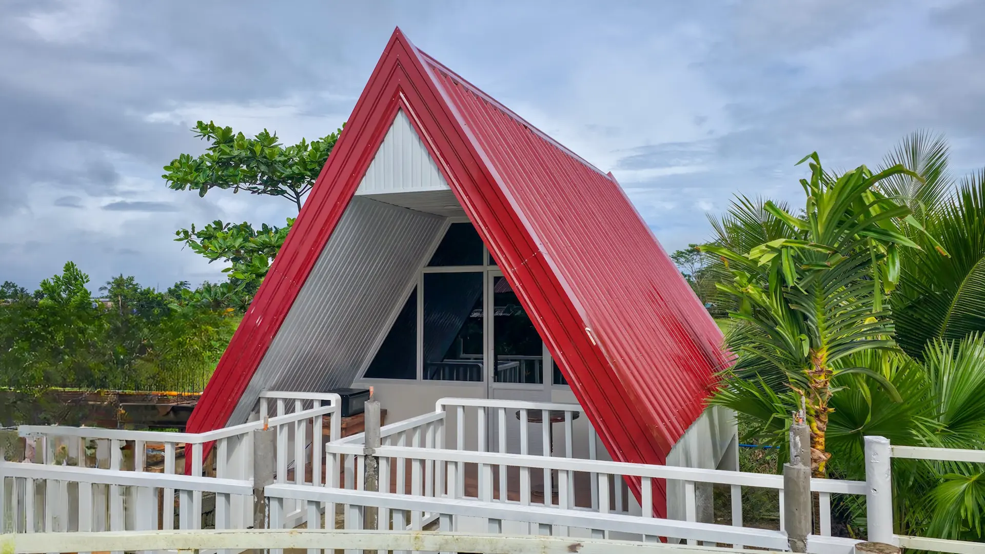 Twin A-Frame Room exterior during the day — A-frame architecture with tropical landscaping